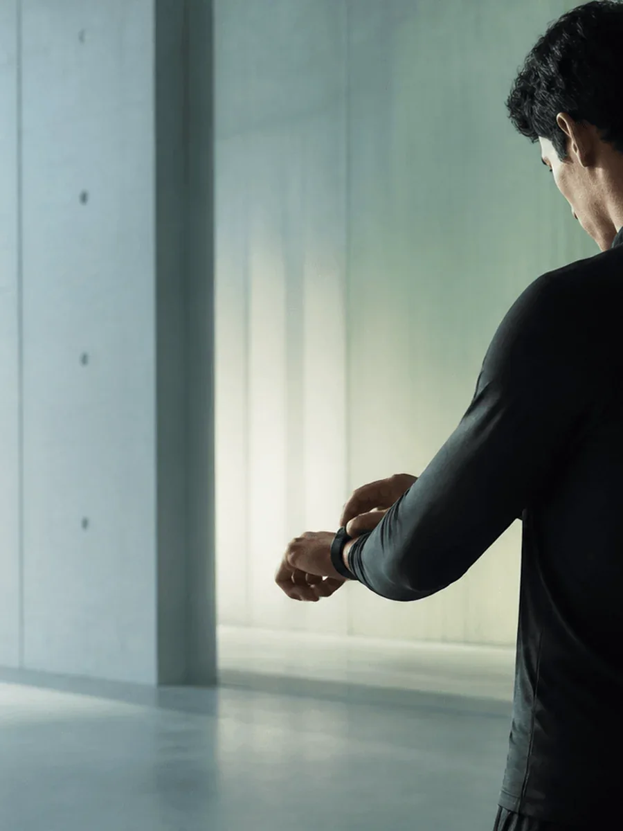 An athlete checking a wrist monitor in cold morning light